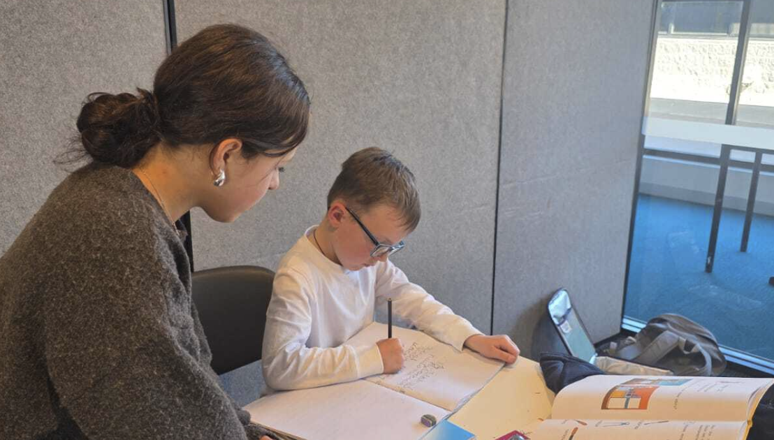 Teacher supporting a student with written Russian exercises